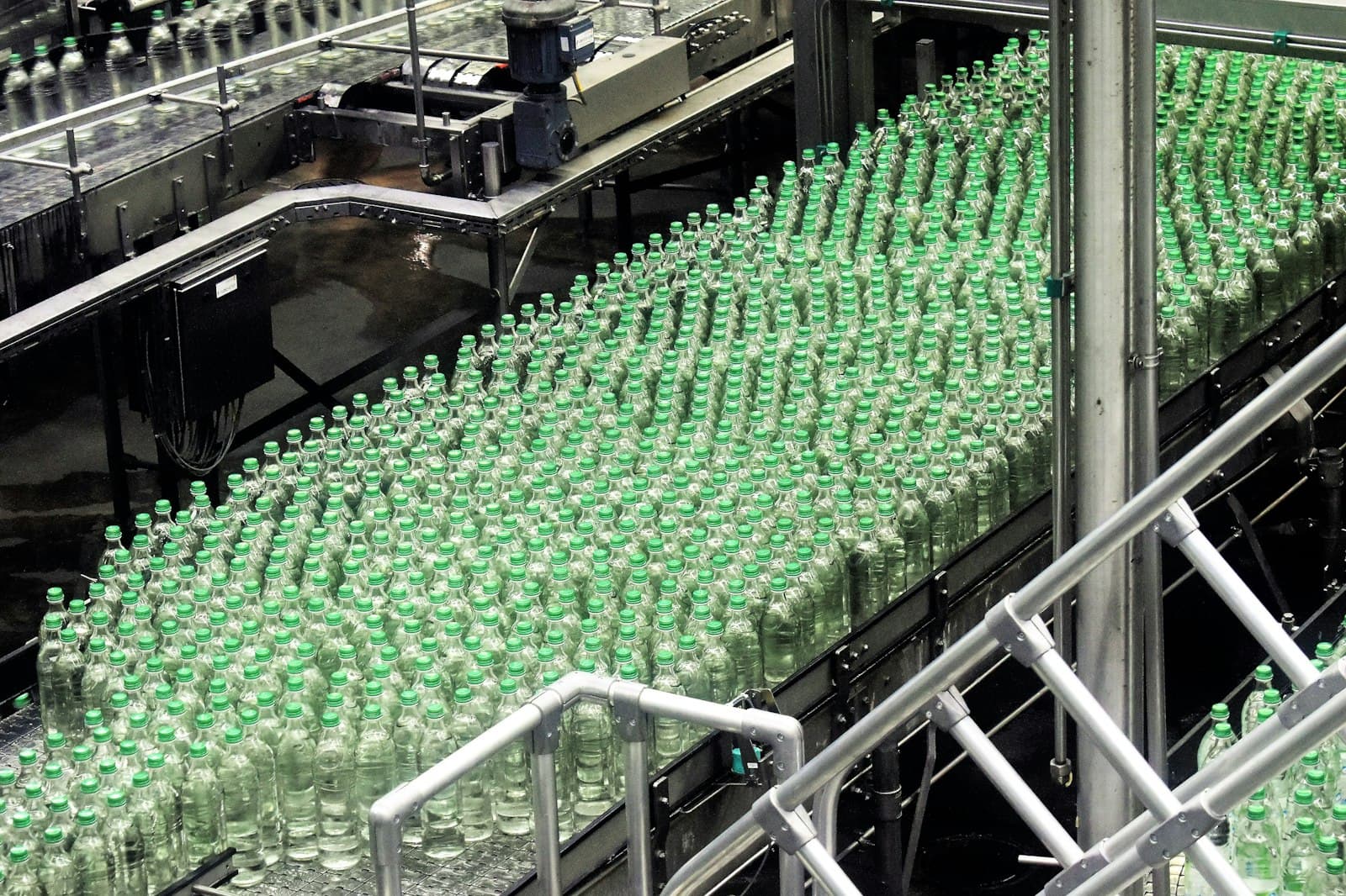 Rows of green bottles moving along a beverage bottling line conveyor