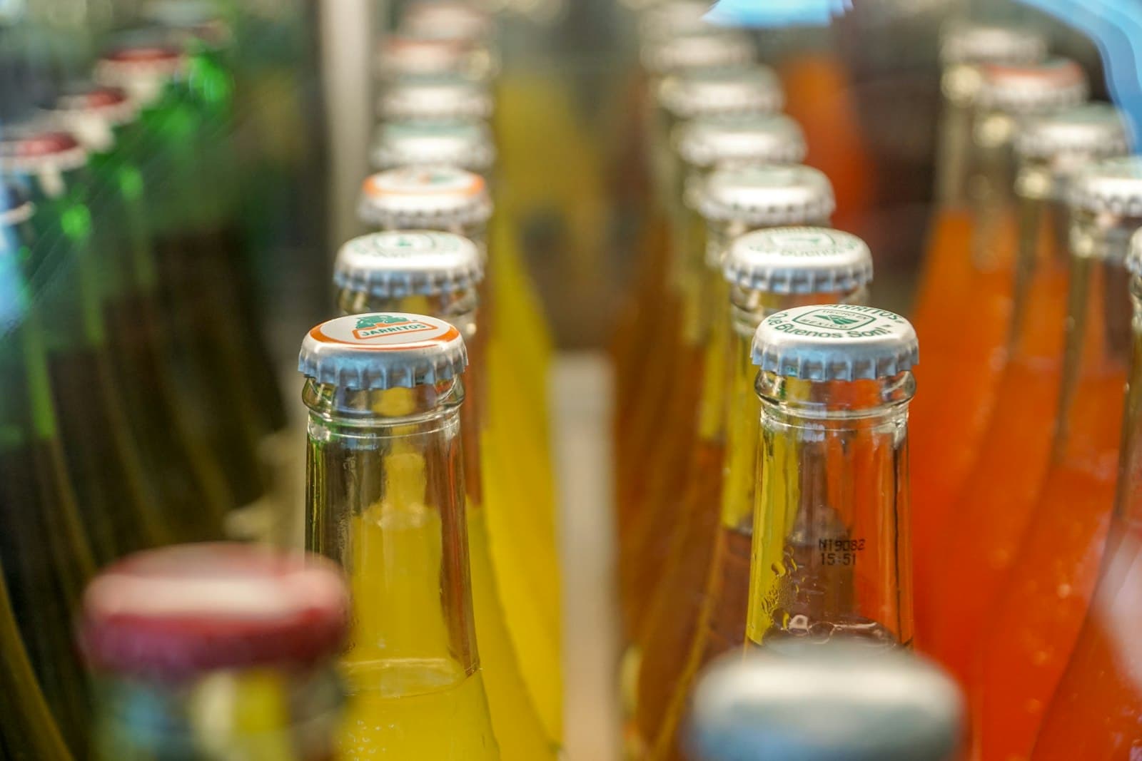 Close-up of filled orange and yellow carbonated drink bottles with crown caps