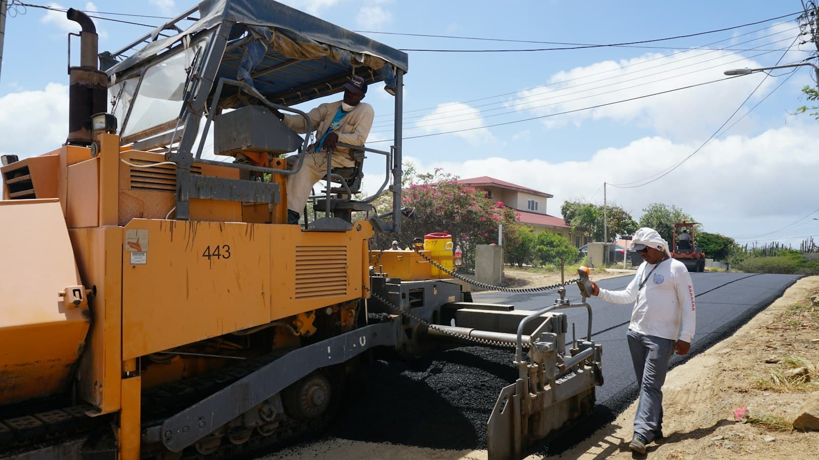 Asphalt paving machine laying a road surface with a supervisor beside it