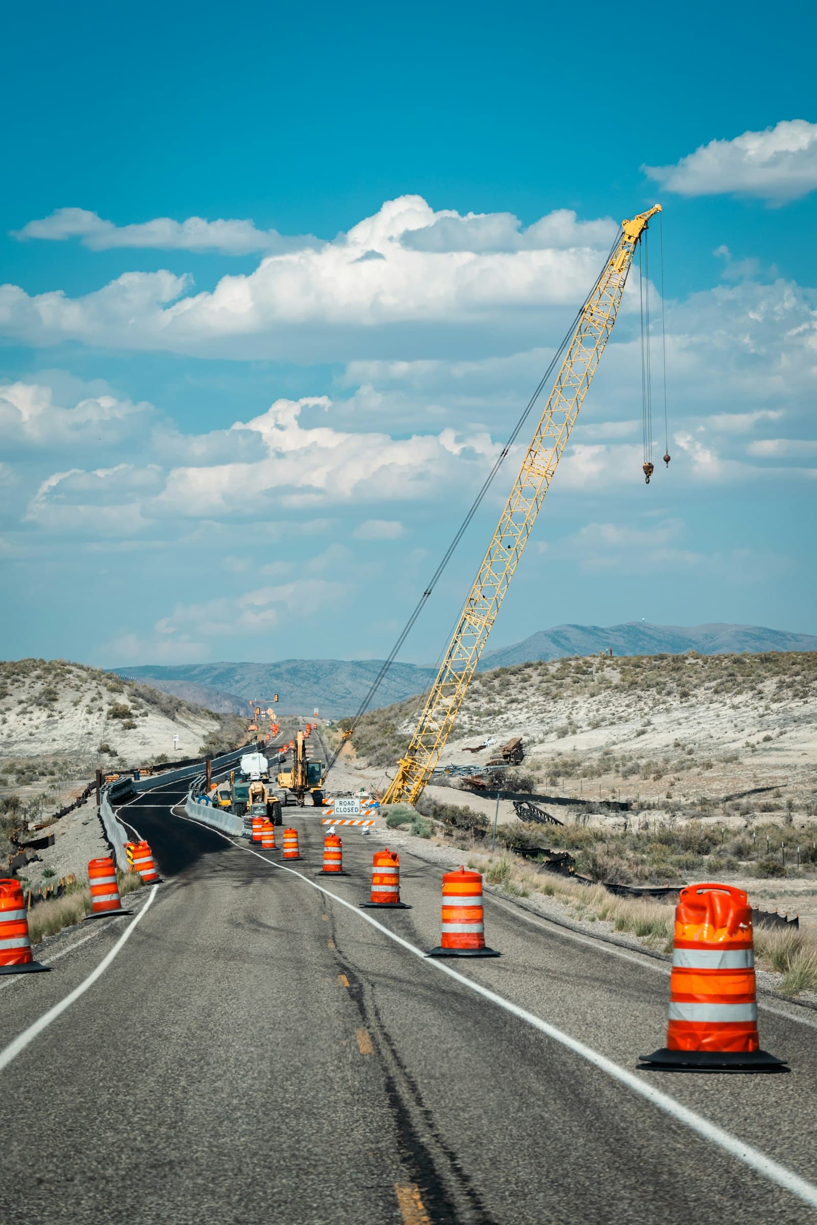 Highway construction on a hillside with a crawler crane and traffic cones