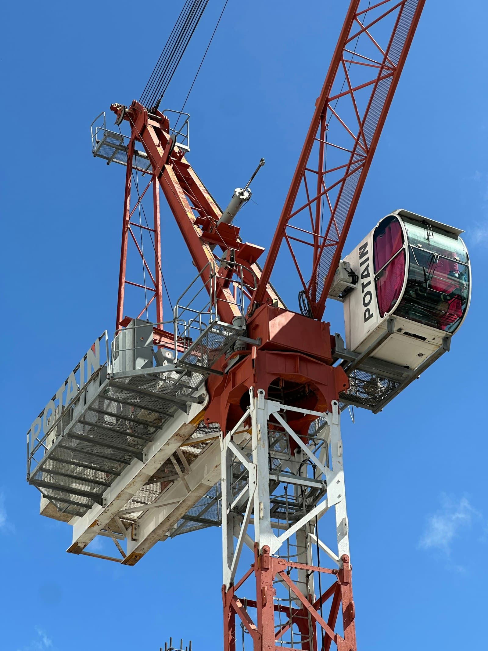 Close-up of a red tower crane with its operator cab seen from below