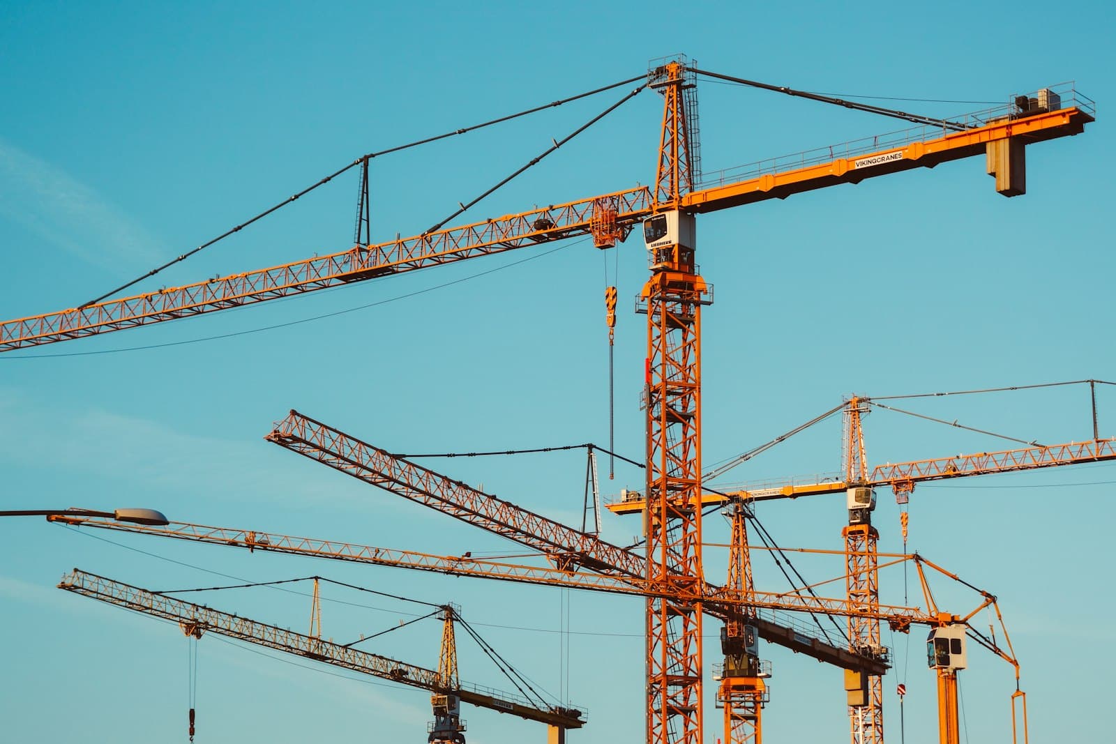 Several tower cranes against a clear sky above a large building project